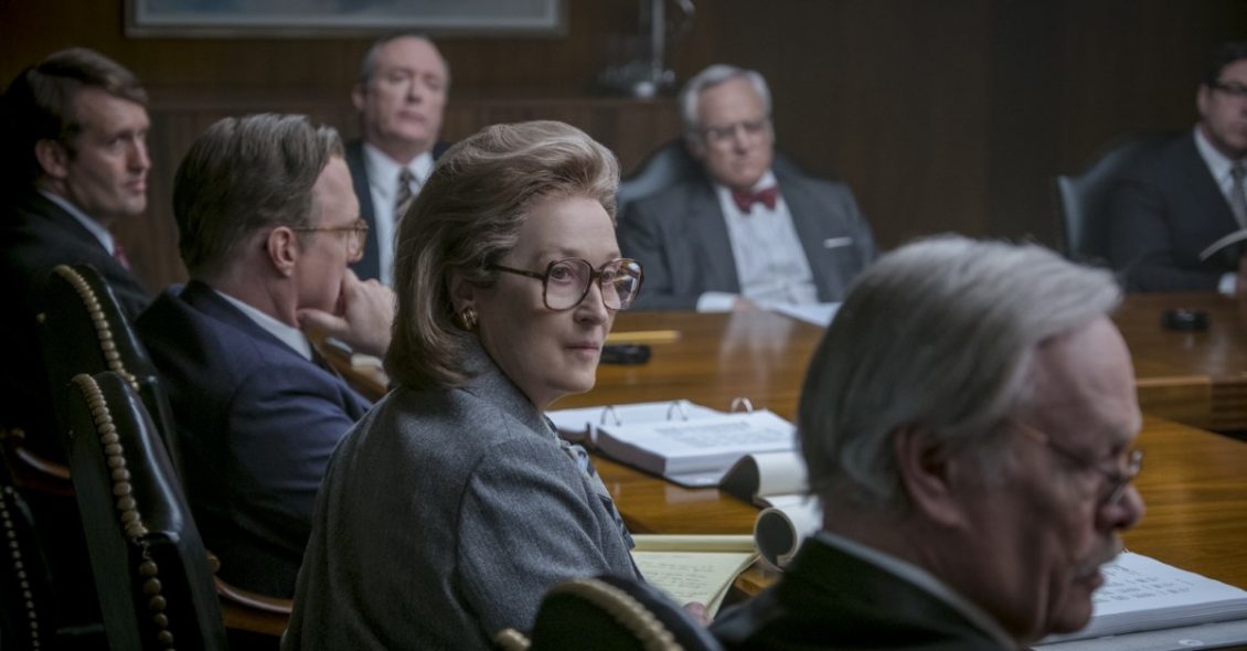 Foto da cena em que a atriz Meryl Streep está sentada à mesa com vários homens.