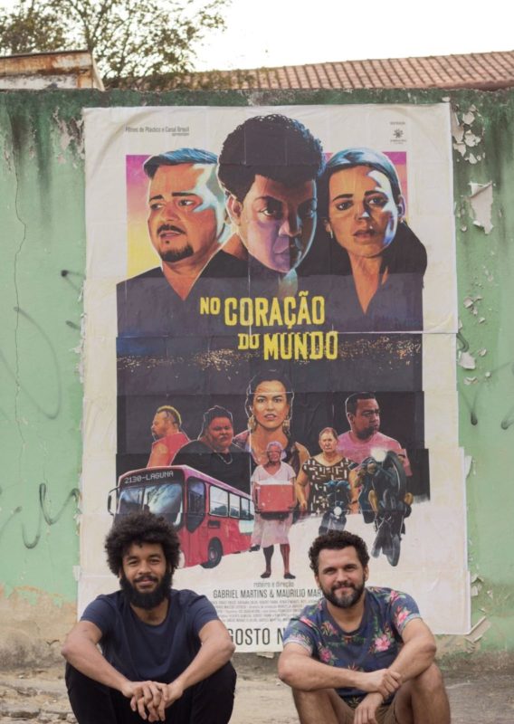 Gabriel Martins e Maurilio Martins, diretores de No Coração do Mundo, sentados em frente ao cartaz do filme - foto: Isabela Martins